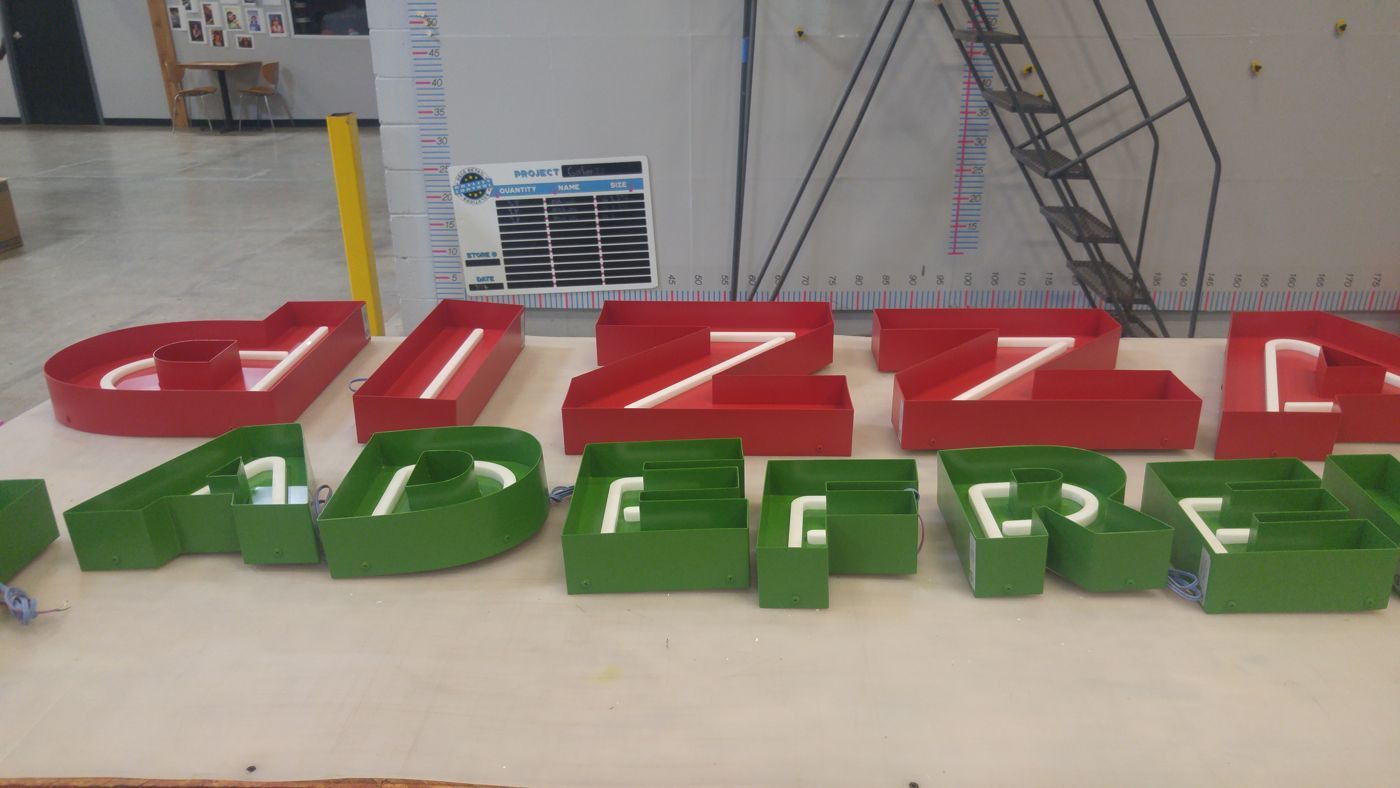 Red and green channel letters for illuminated restaurant sign during fabrication in Atlanta